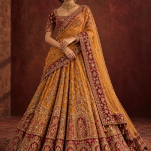 Saffron amber lehenga with burgundy borders and gold embroidery, photographed full length in a professional studio